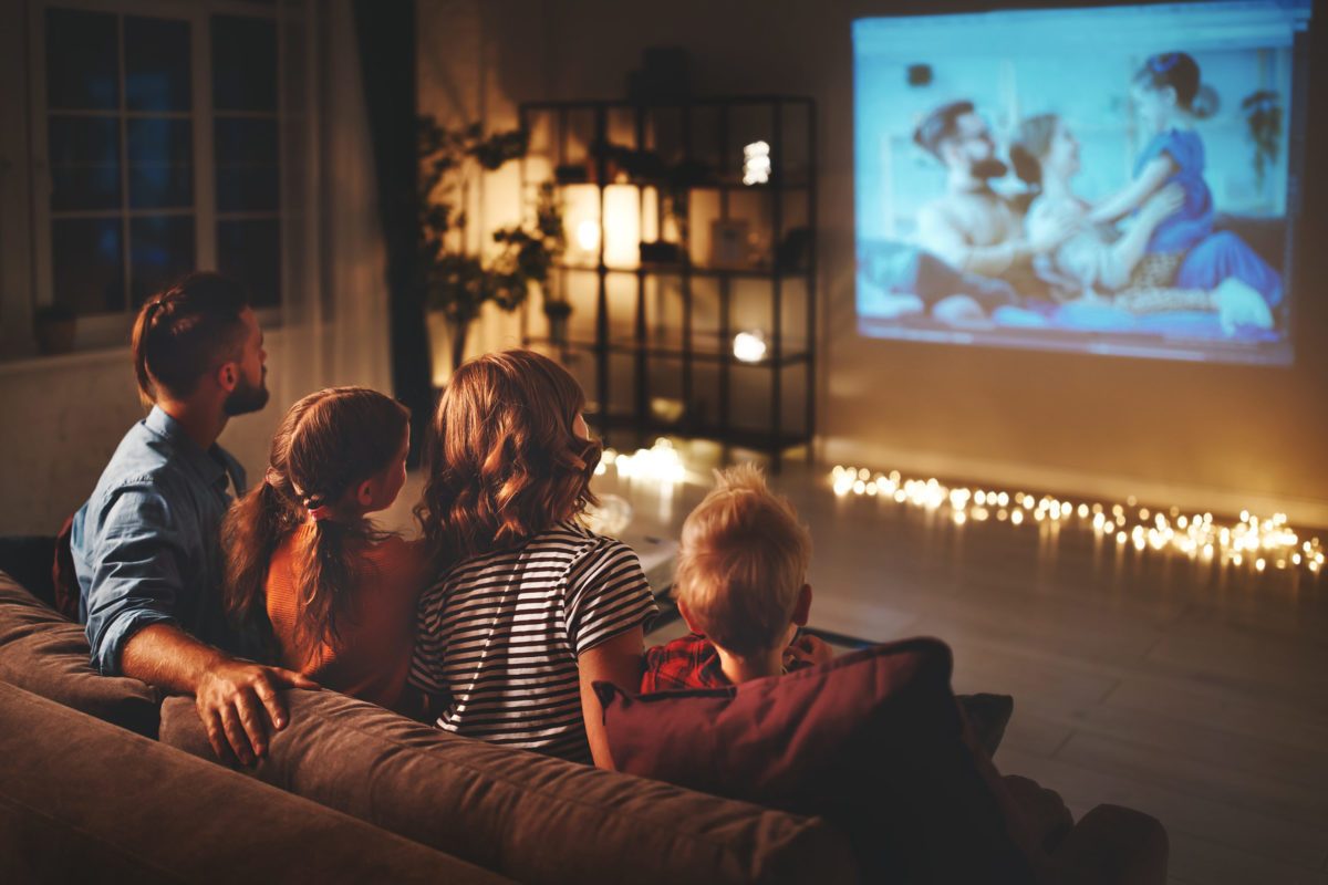 family-mother-father-and-children-watching-projector-tv-movies-with-popcorn-in-evening-at-home